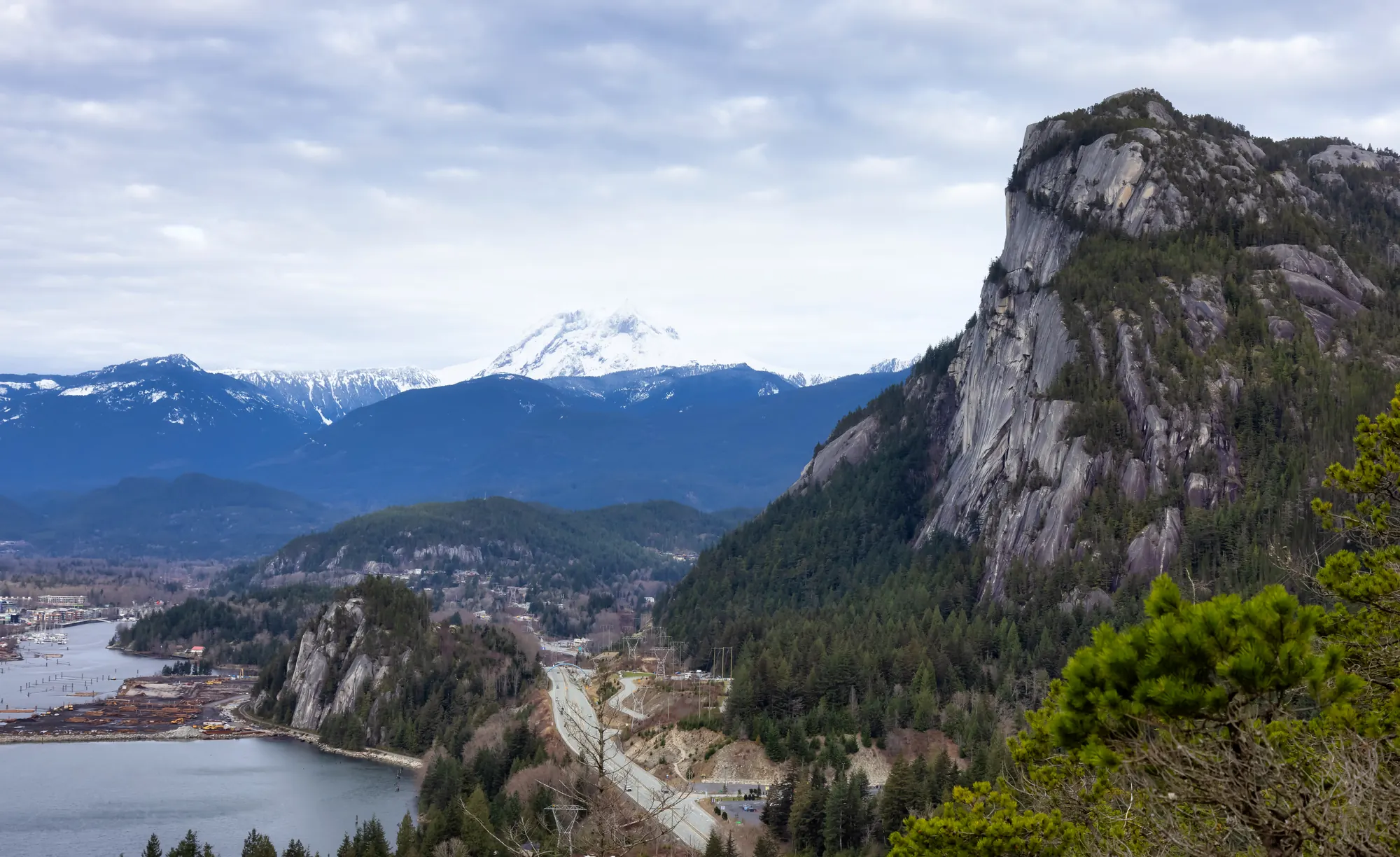 The Stawamus Chief above Howe Sound in Squamish, BC, with snow-capped mountains behind